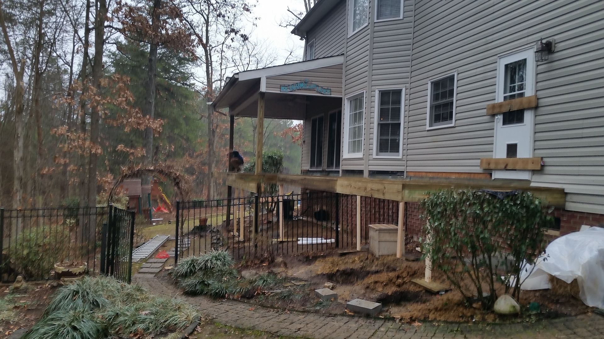 Backyard with a house, partially constructed deck, and surrounding landscaping.