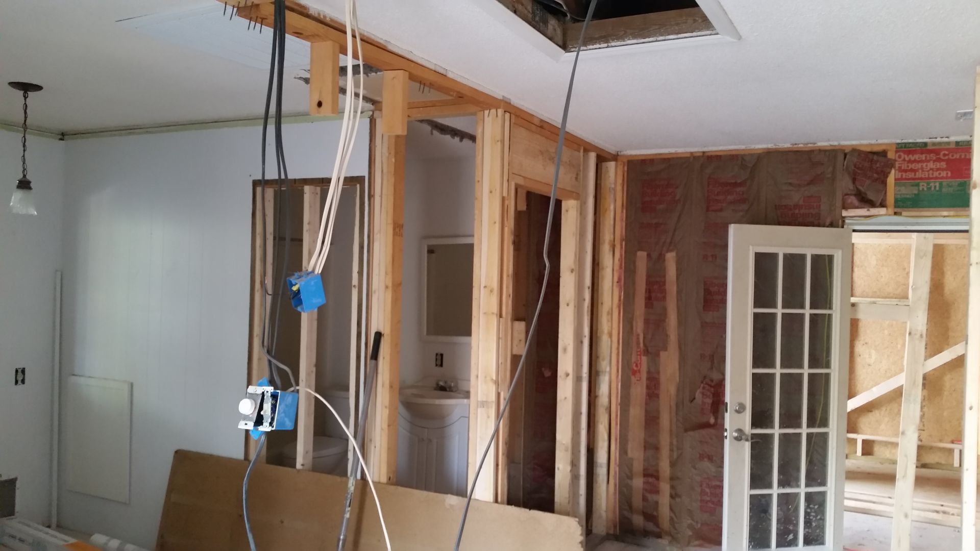 Interior room under construction, with exposed framing, plumbing, and electrical wiring.