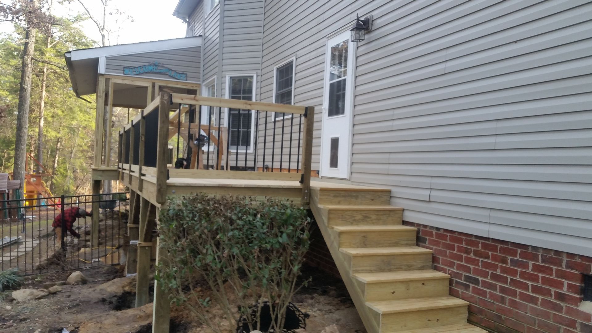 Wooden deck and stairs attached to a two-story house with gray siding.