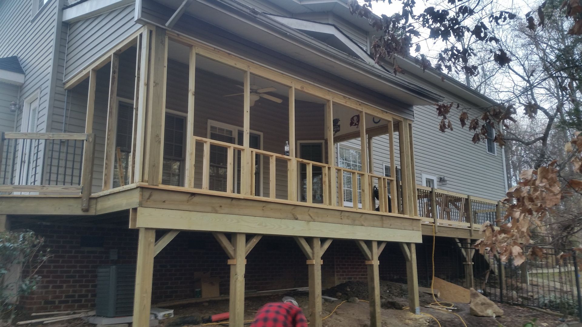 Wooden deck addition on a house; screened porch and elevated deck; construction underway.