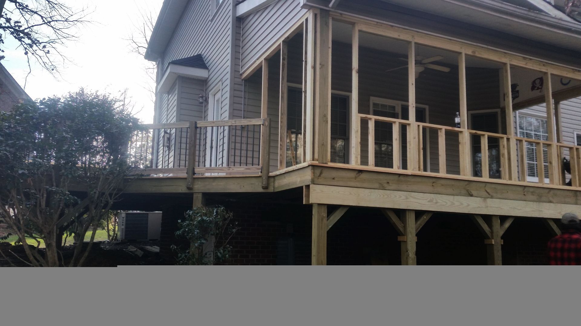 Wooden deck and screened porch attached to a two-story house.