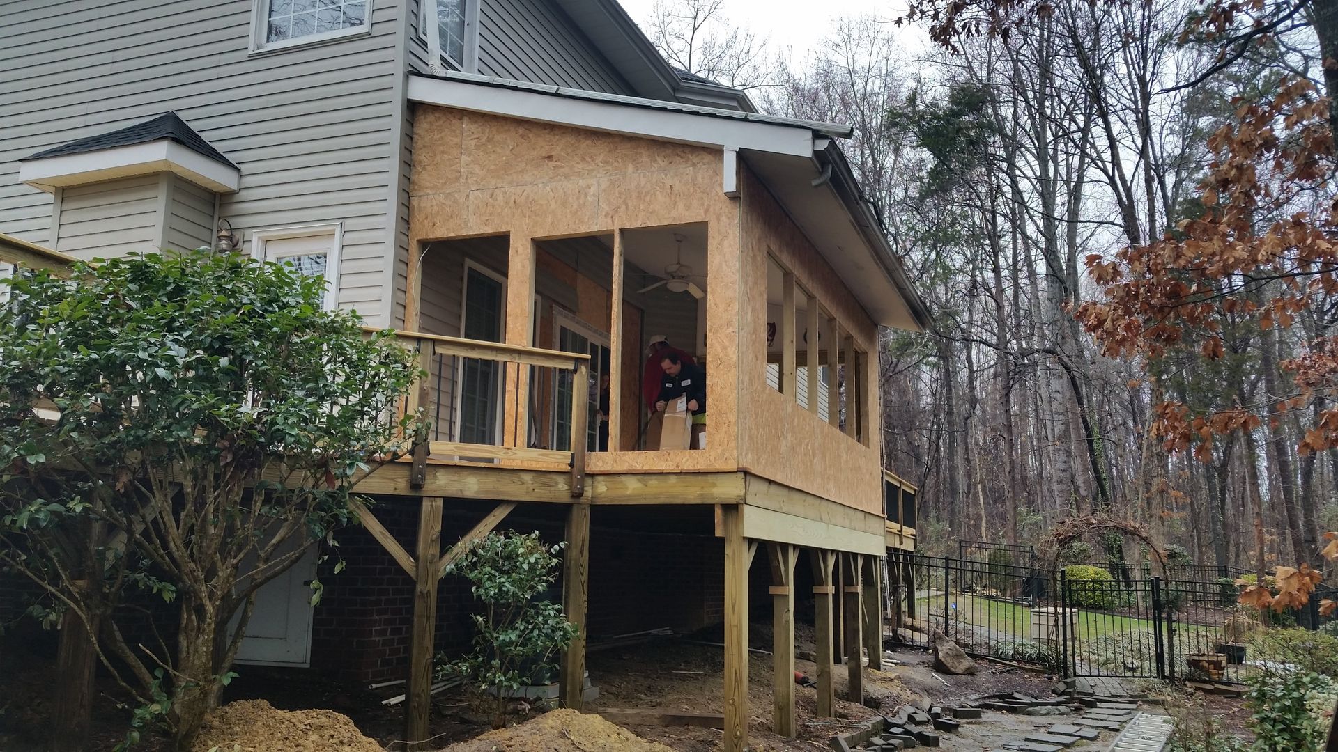 Construction of a raised deck with a wooden frame attached to a house. Exterior view.