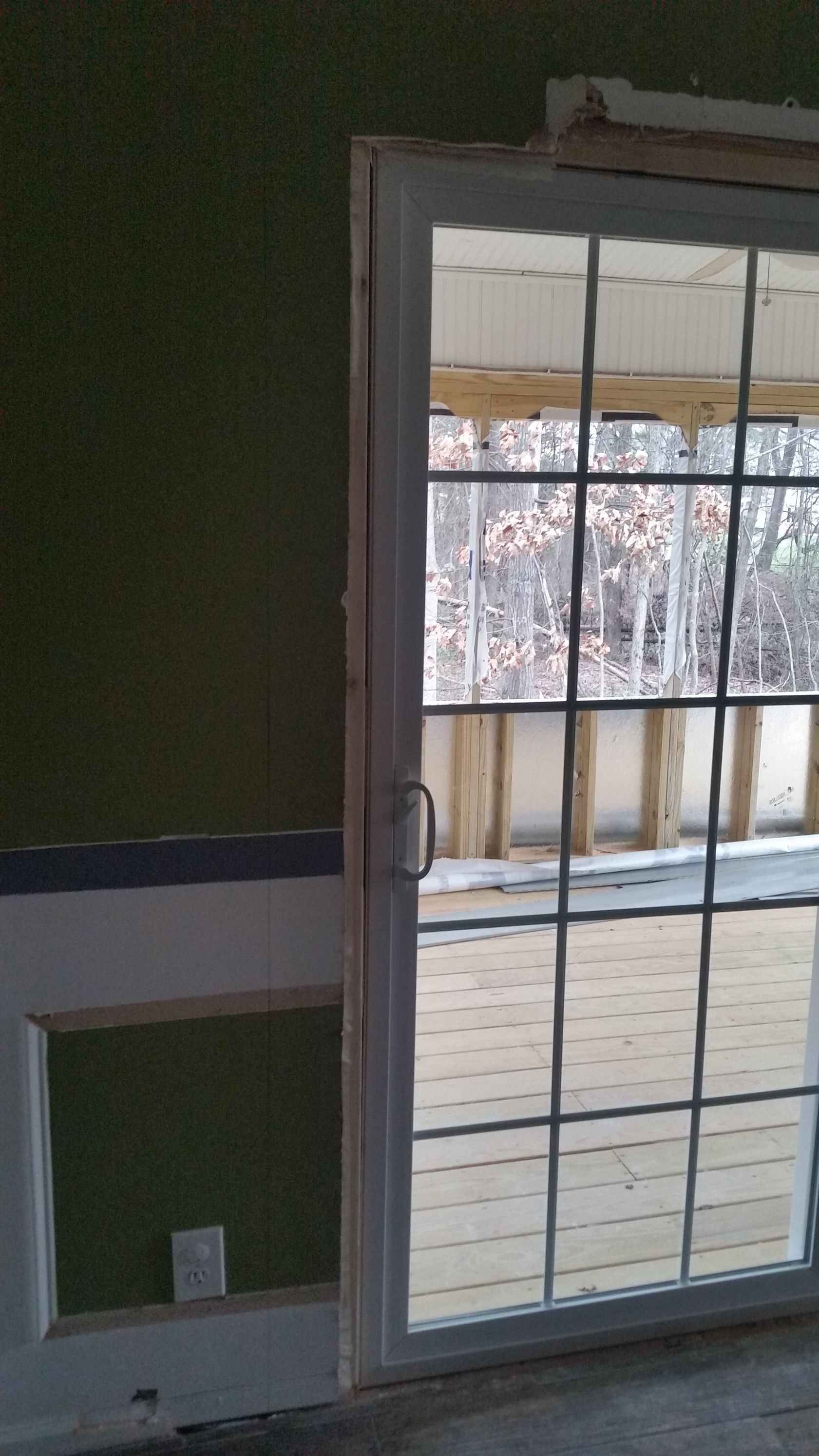 Interior view of a sliding glass door with a grid pattern, an open wall, and an electrical outlet.