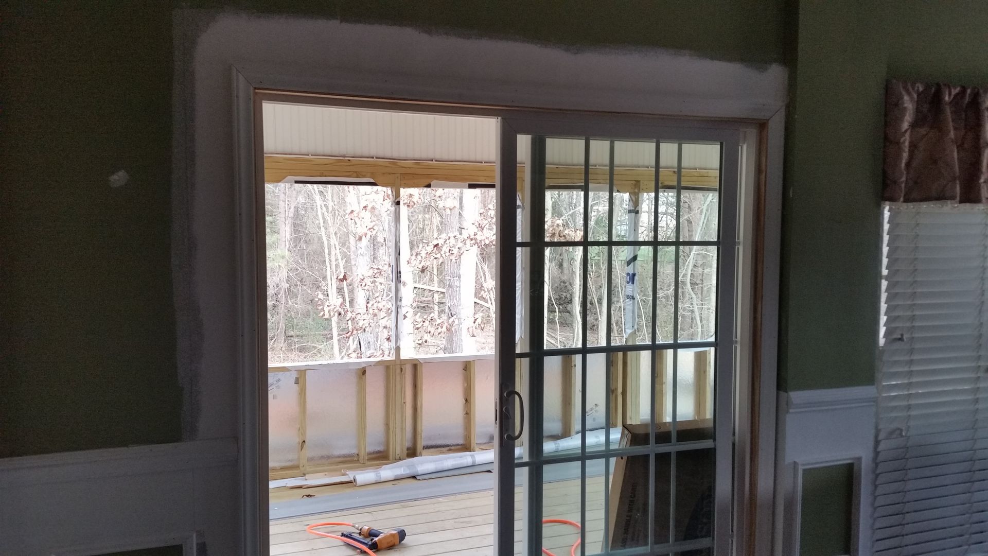 Sliding glass door opening to a sunroom. Interior view with white trim and green walls.