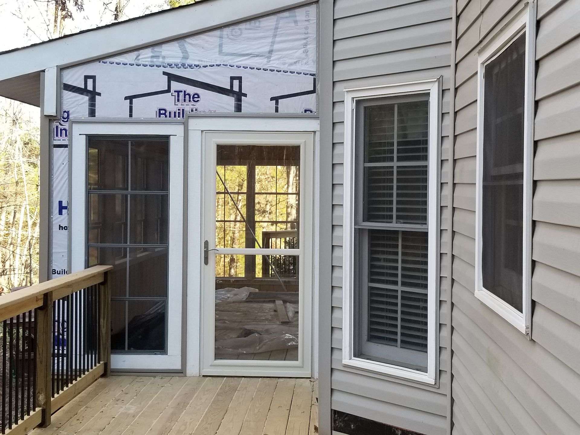 Deck with screen door and window, tan siding, wood deck, screen.