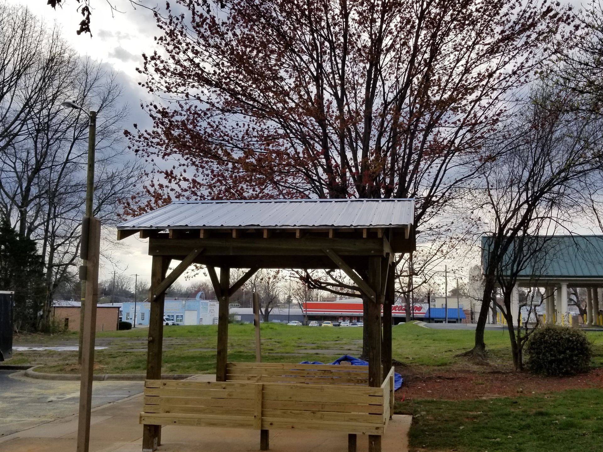 Wooden shelter with metal roof in a park.