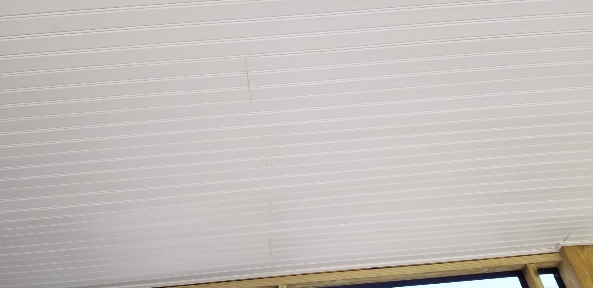 White panel ceiling with horizontal lines. Wooden frame visible at the bottom.