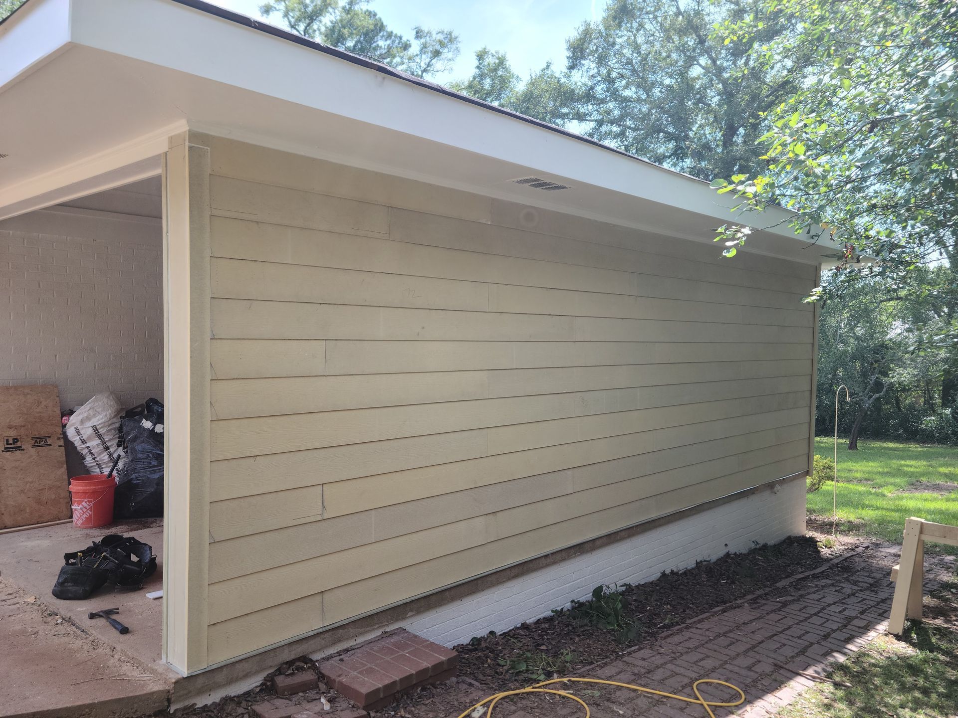 Exterior of a building with light green horizontal siding and a white roof overhang.