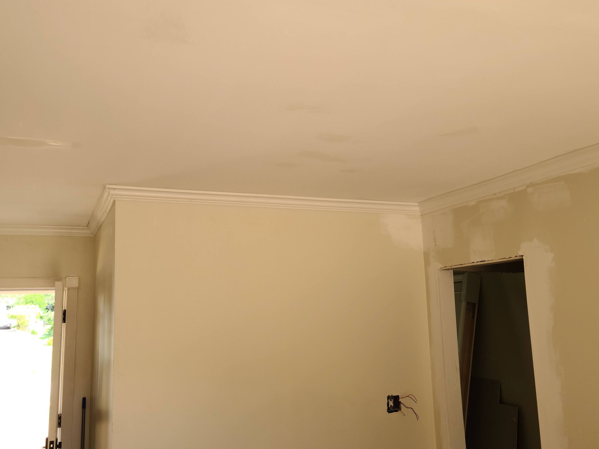 Interior view of a room with light-colored walls, crown molding, and an unfinished doorway.