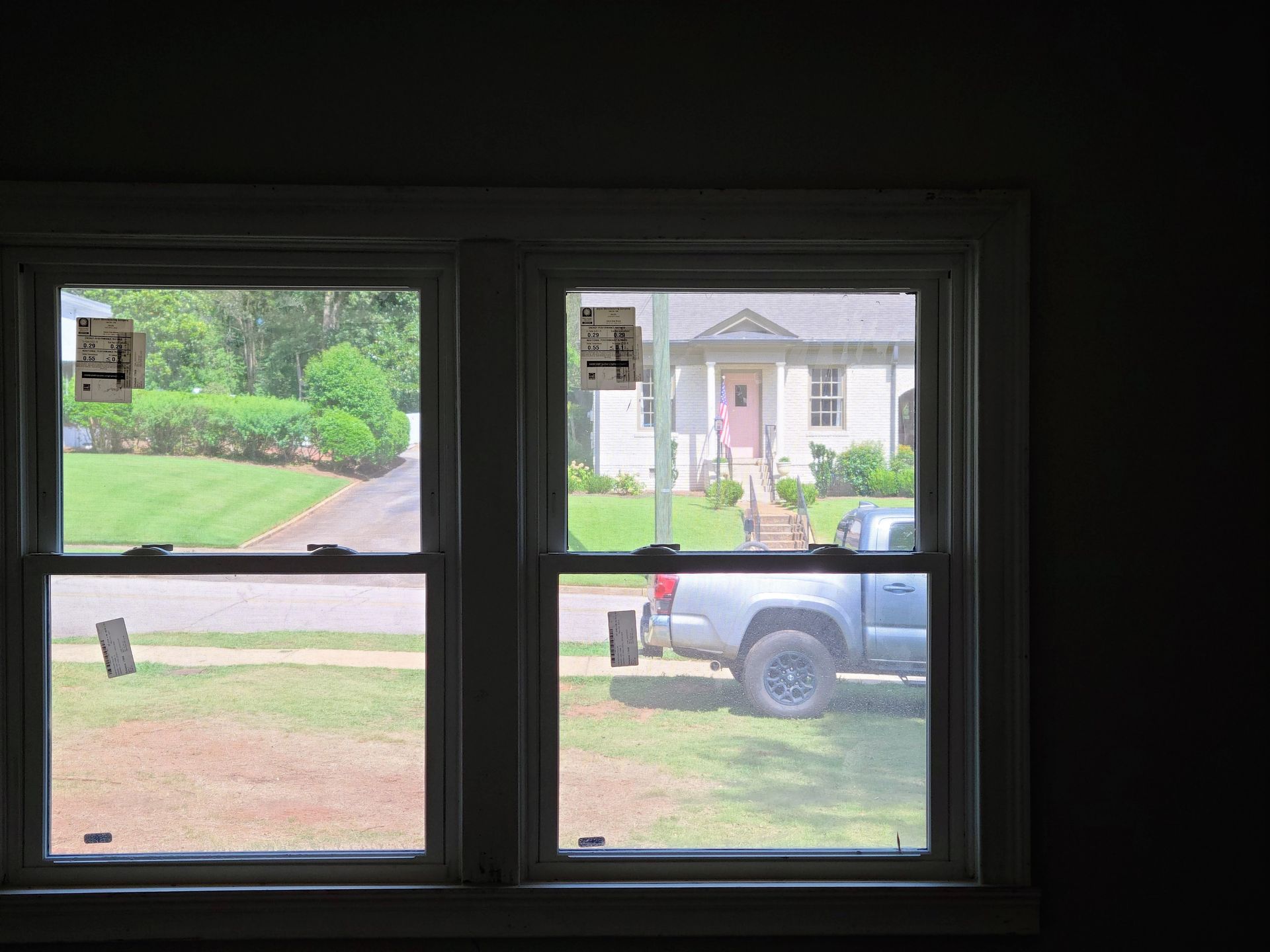 View through a double window: A house, a truck, and a driveway are visible.