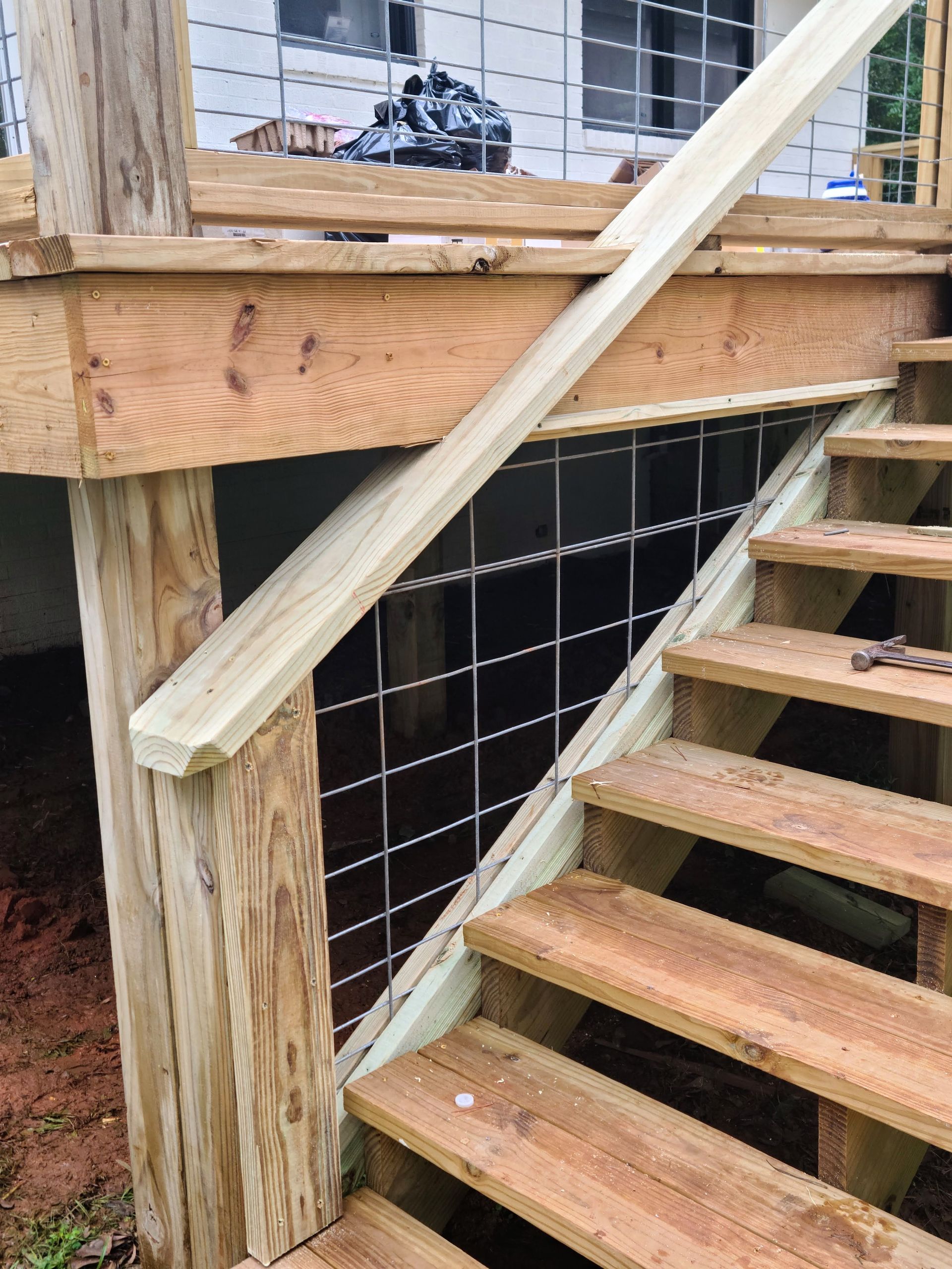 Wooden staircase with wire mesh railing. New construction, outdoors.