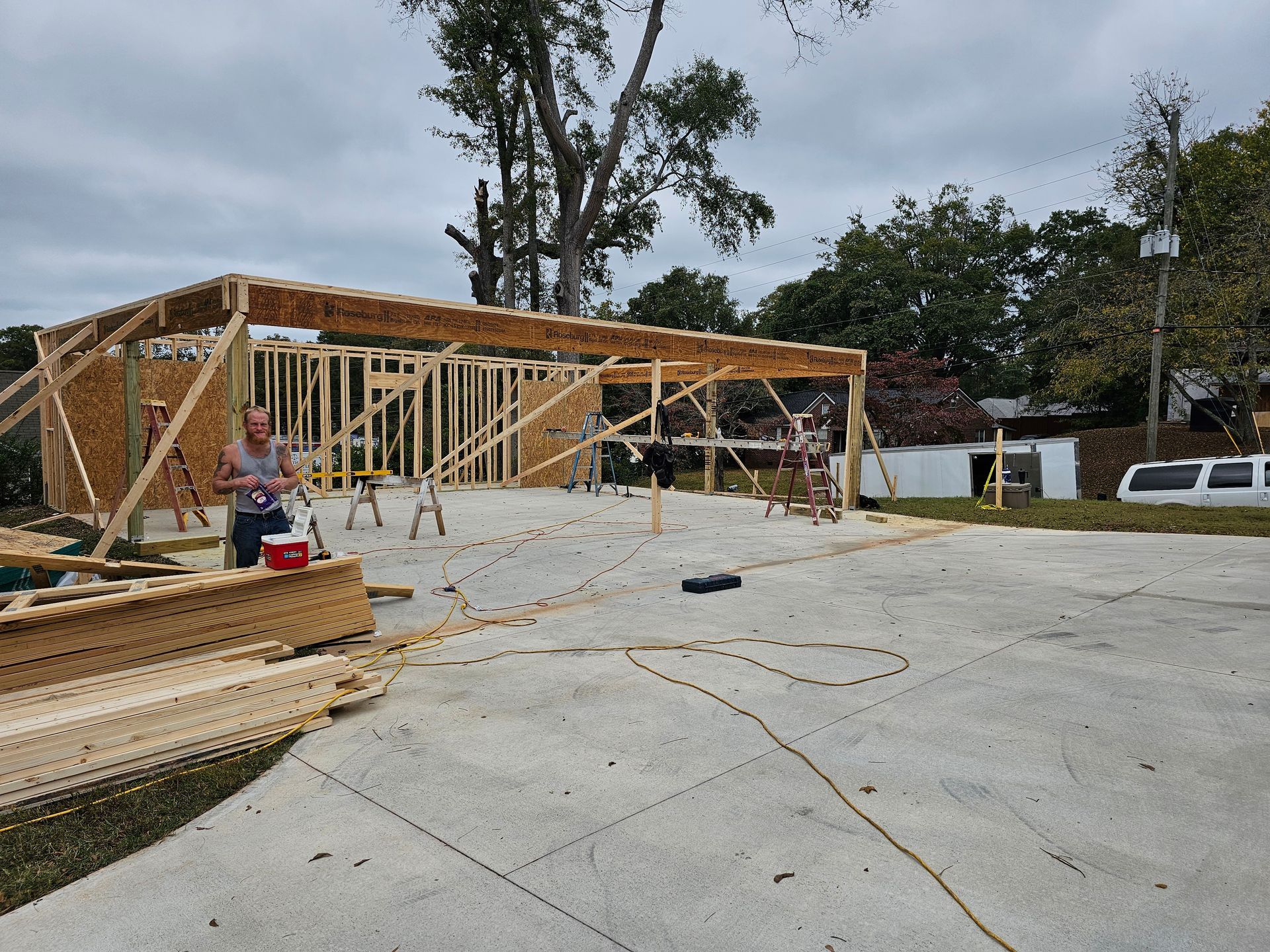 Construction site: wood frame building under construction, person working. Outdoor, overcast day.