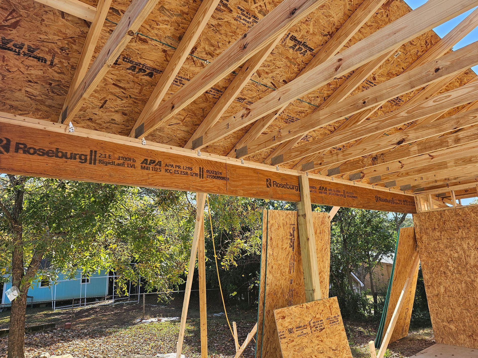 Construction site with wooden beams and roof under construction; Roseburg beam visible.