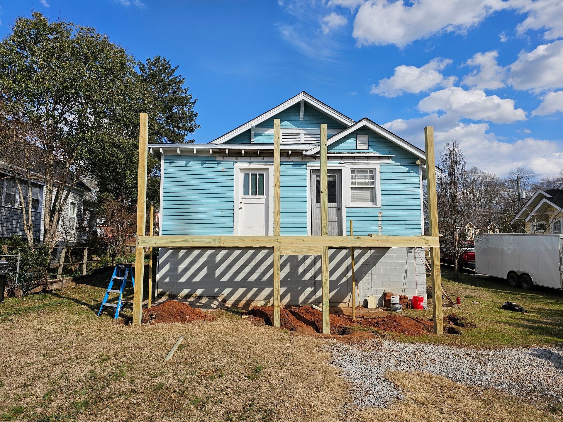 Blue house with a partially constructed wooden deck.