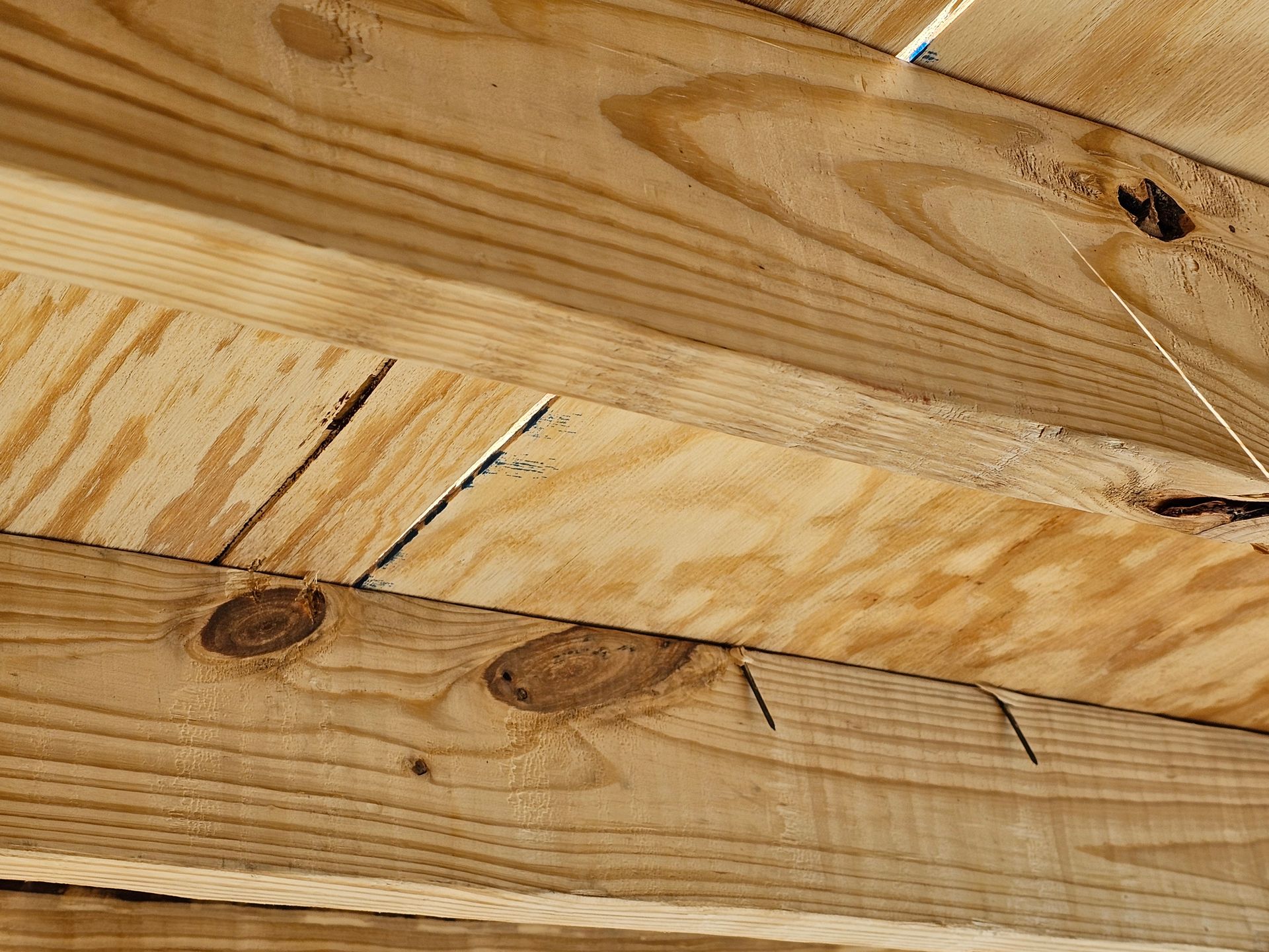 Close-up of wooden planks. Some boards have knots and cracks. Nails protrude from the wood.