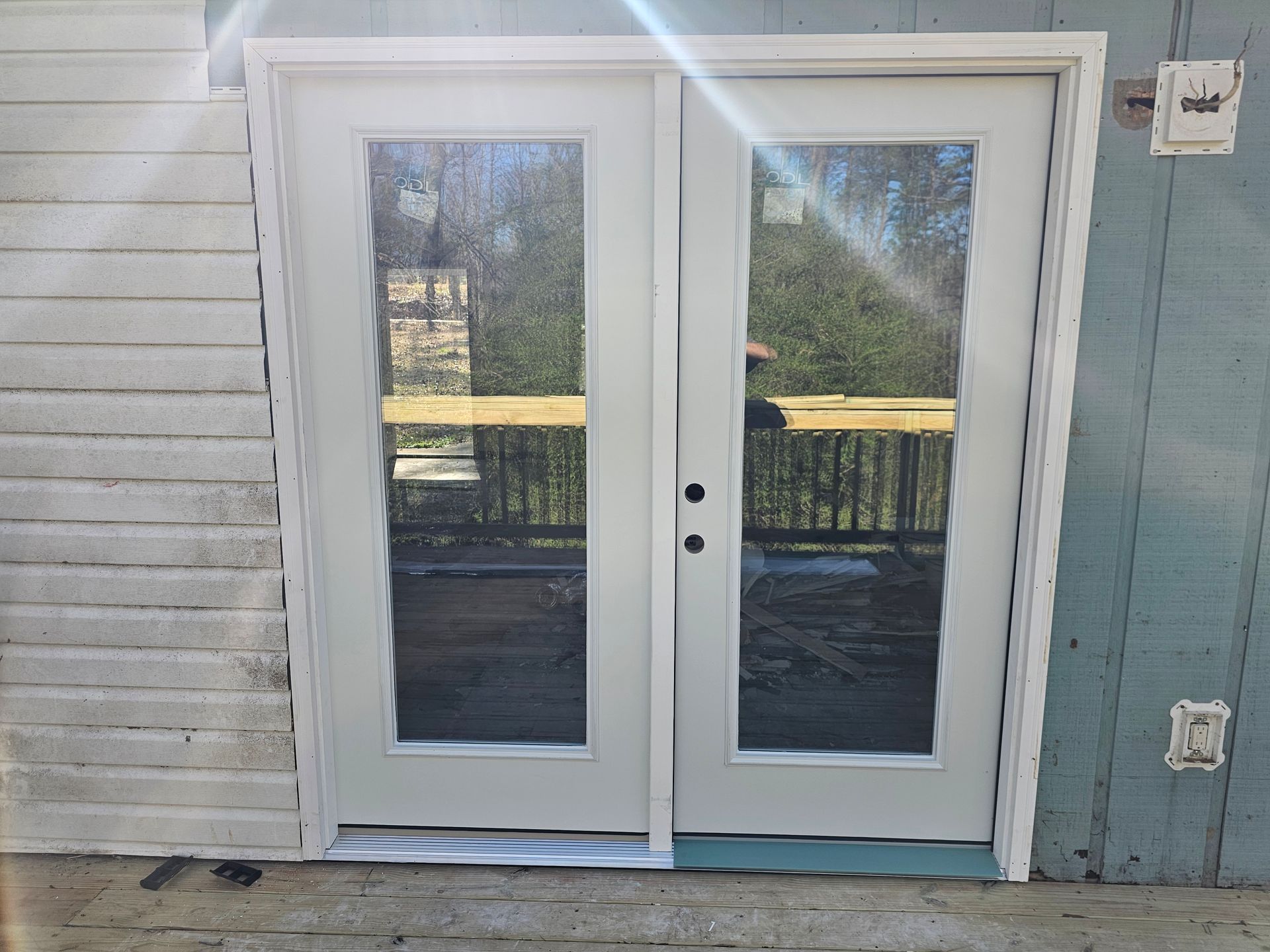 White double doors with glass panels, set in a light-colored frame, on a patio.