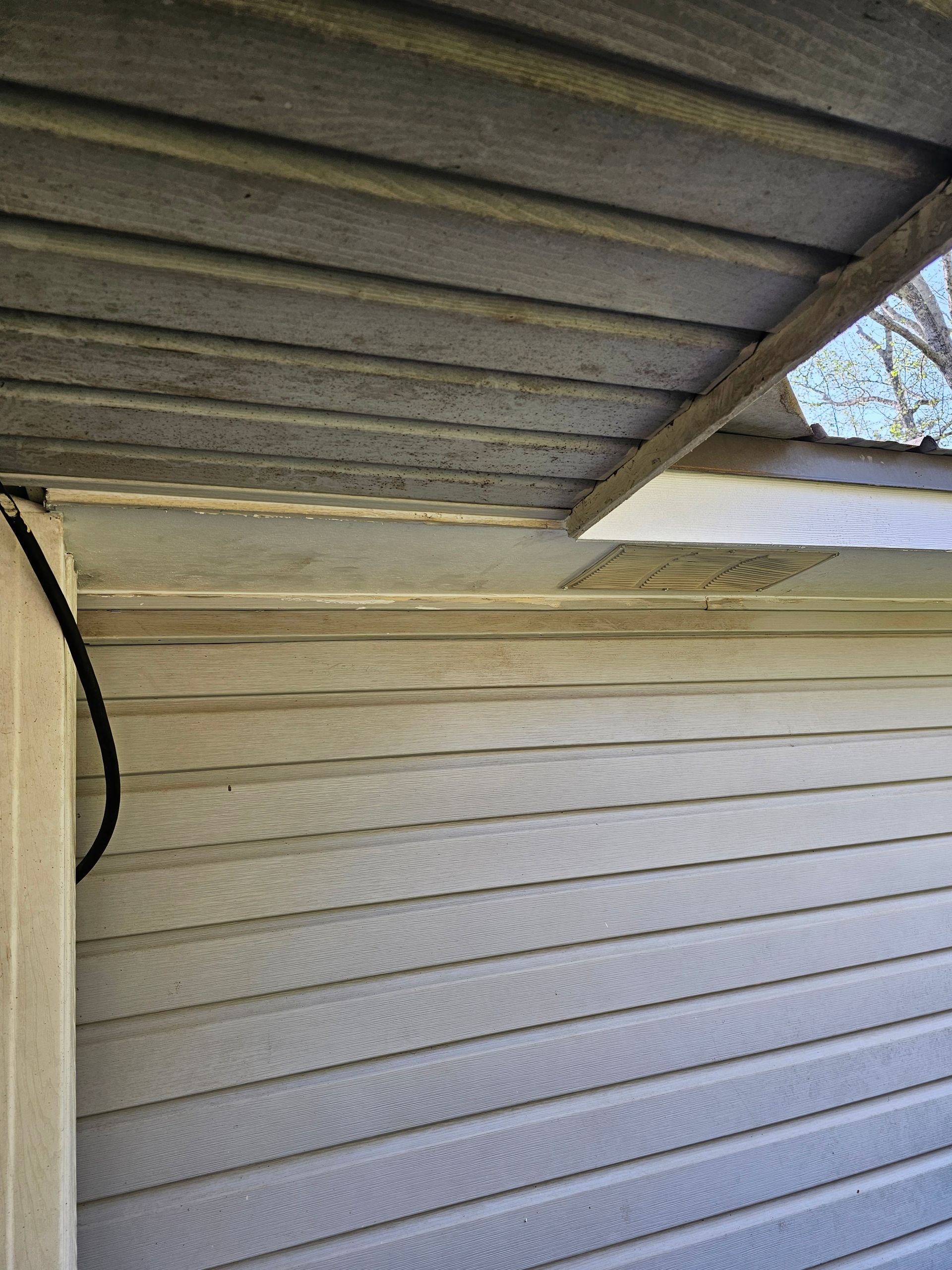 Gray and white siding with weathered wooden paneling and a black cable.