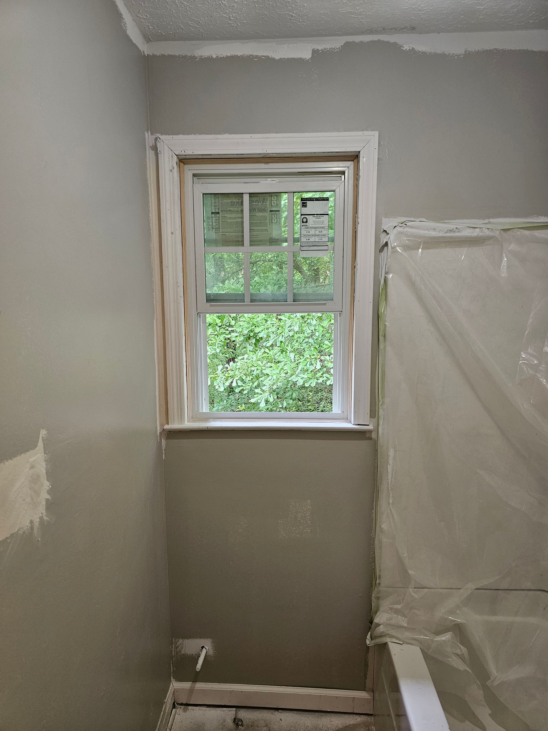 A small, rectangular window framed in white trim in a gray-painted bathroom.