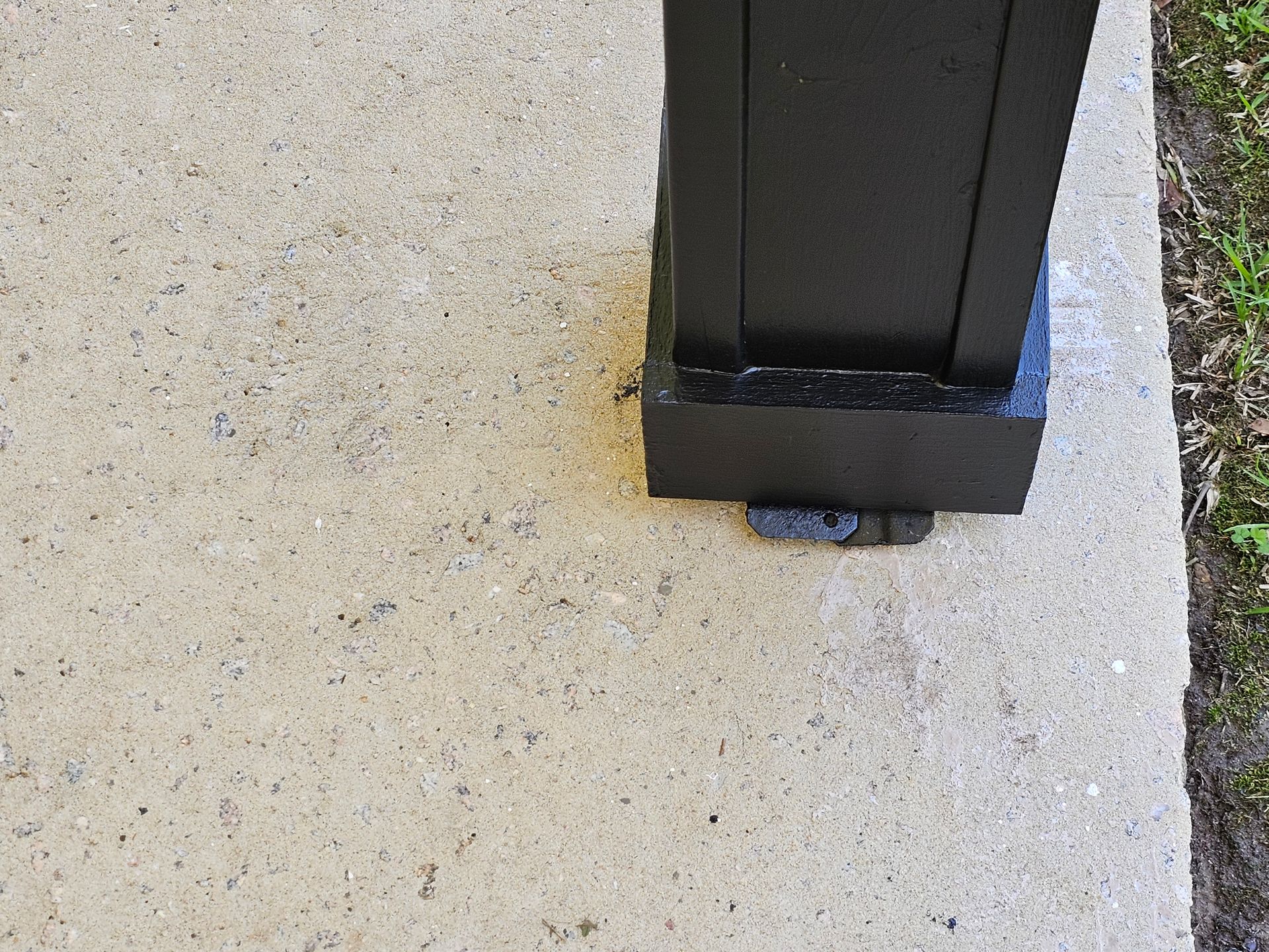 Black post on concrete slab.