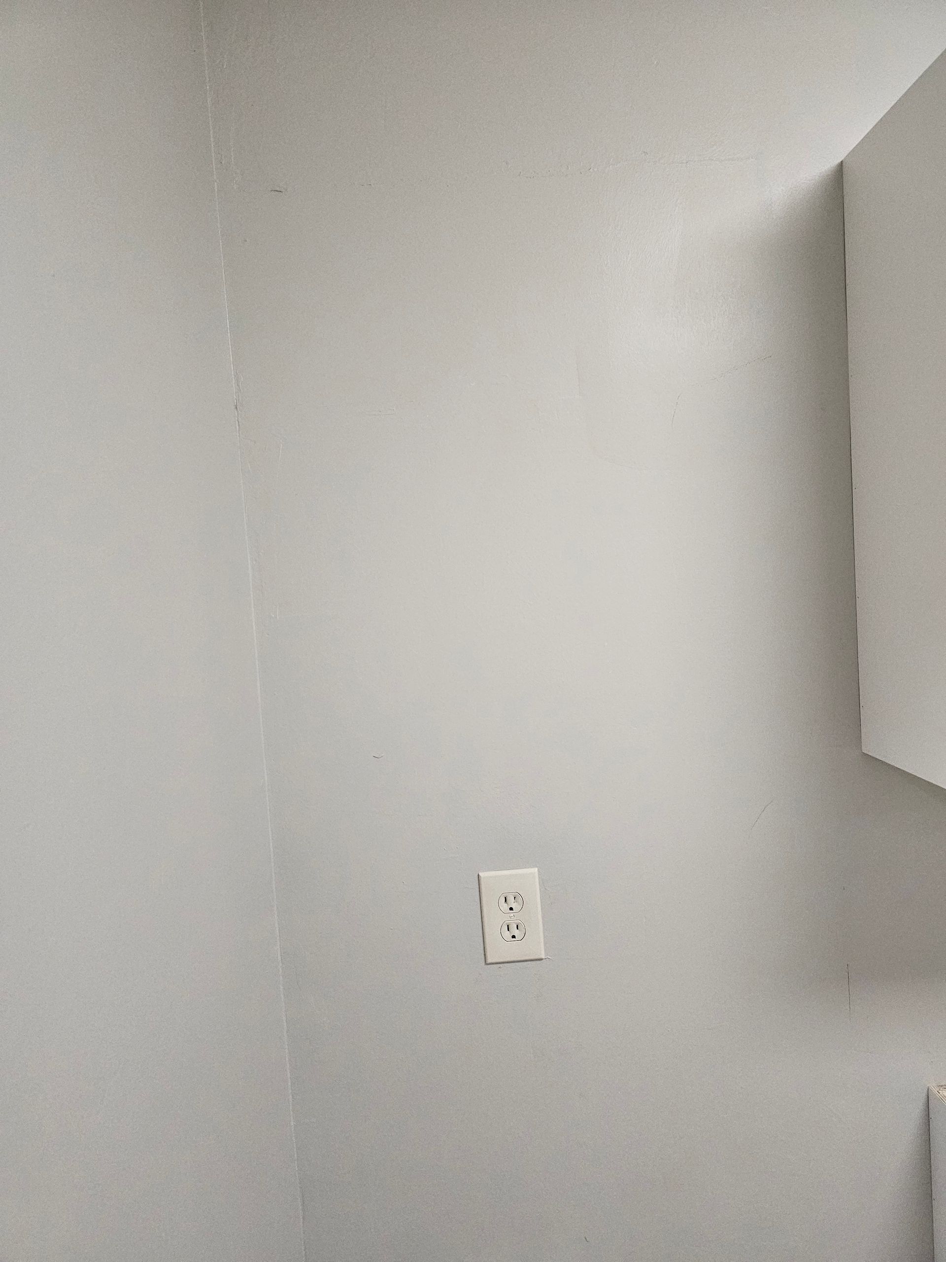 A light gray corner wall with a white electrical outlet.