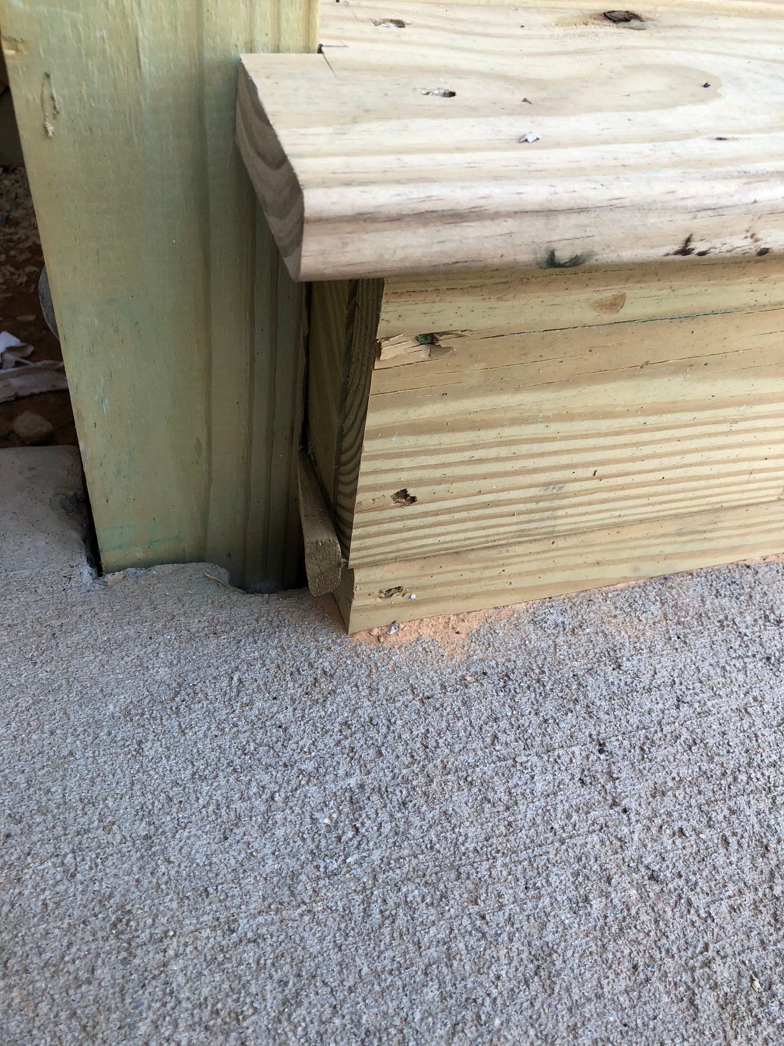 Wooden deck steps, viewed from ground level. Light-colored wood, sitting on gravel.