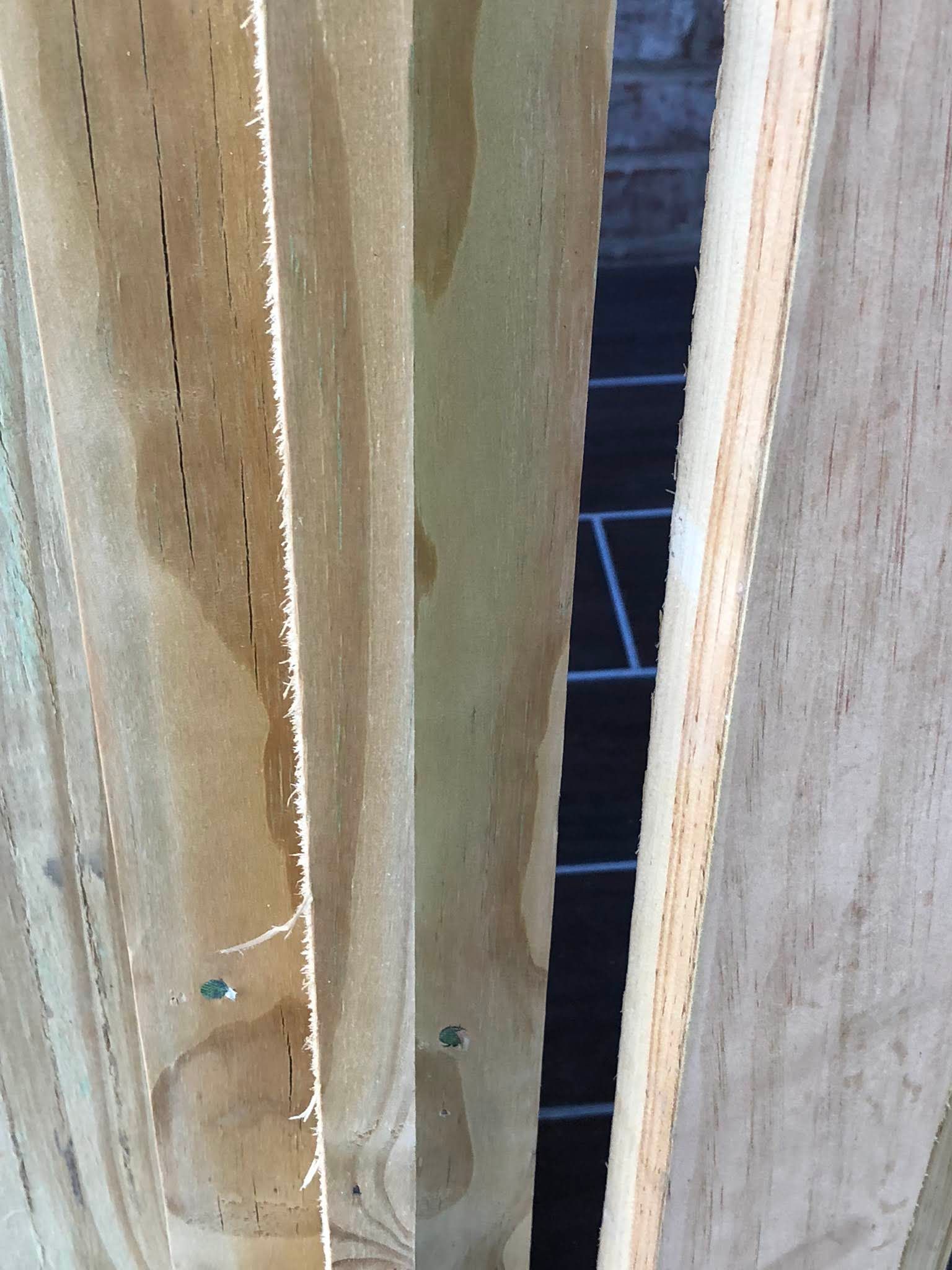 Wooden boards stacked closely together, revealing a glimpse of a dark, shadowed space.