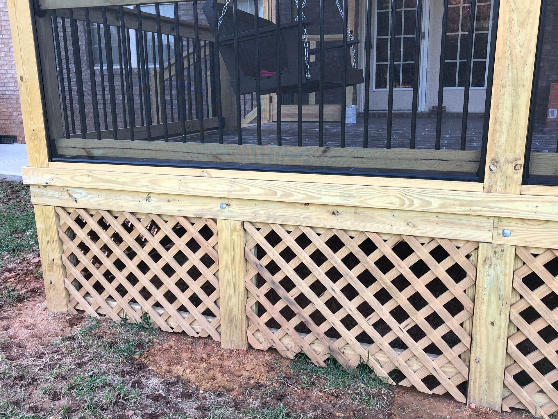 Wooden deck with lattice skirting and black railing.