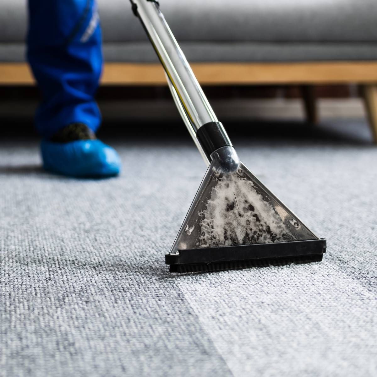 A carpet cleaning machine in use, showing a clear contrast between cleaned and soiled areas of the carpet.