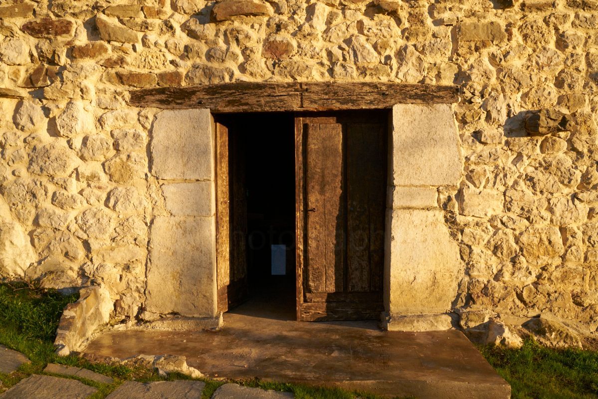 Entrada de piedra y madera a la sala de reuniones, iluminada por la dorada luz de la tarde.