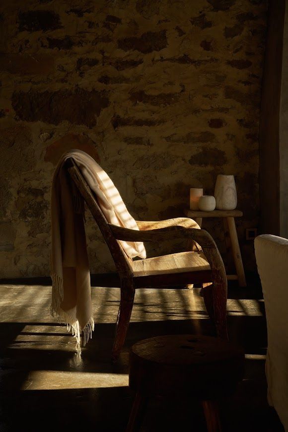 Detail of a primitive chair. 500 years old. Stone wall, wool blanket, and wabi sabi alabaster chandeliers.