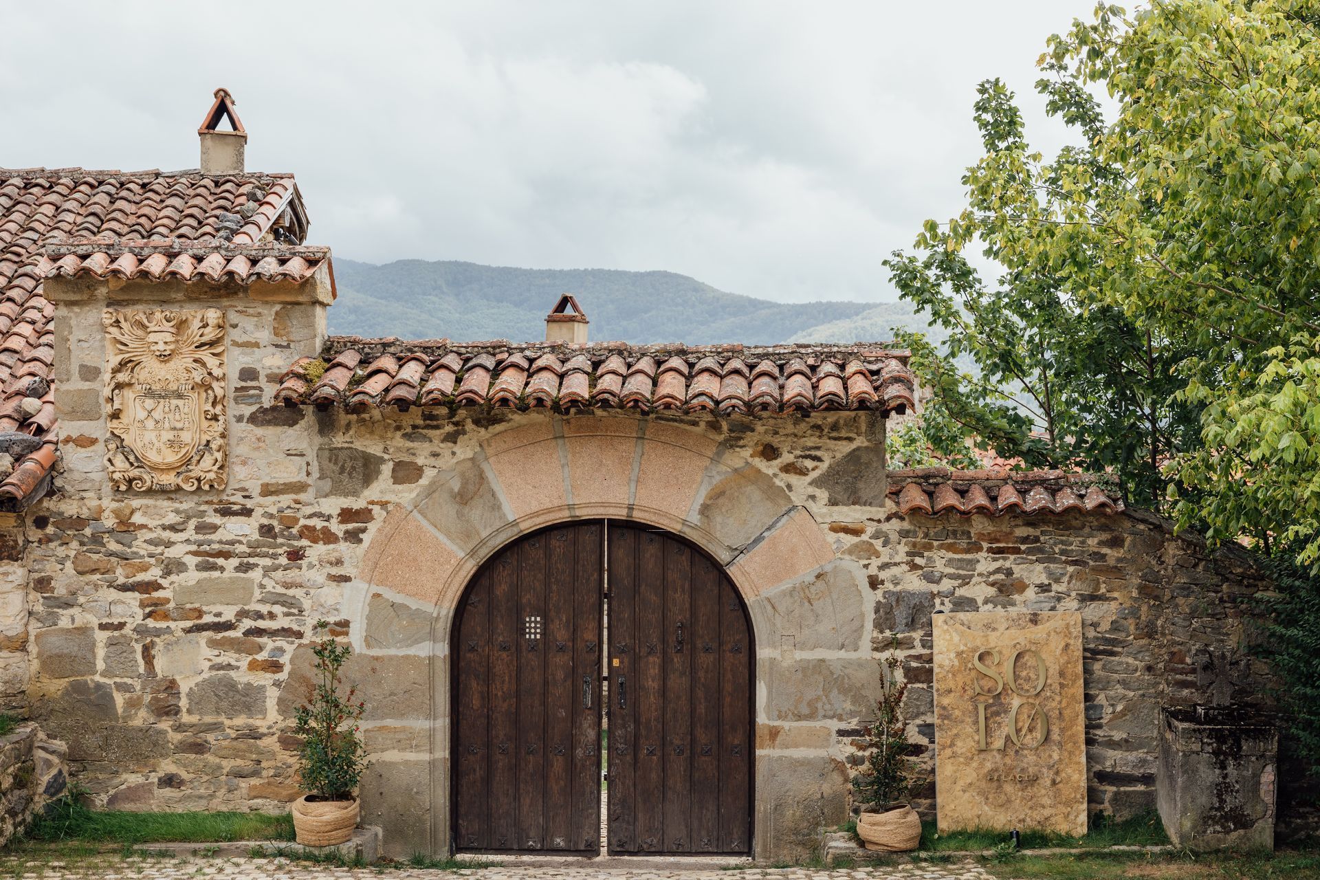 Entrance through the main door of the palace. Stone and wood arch. Large raised brass sign.