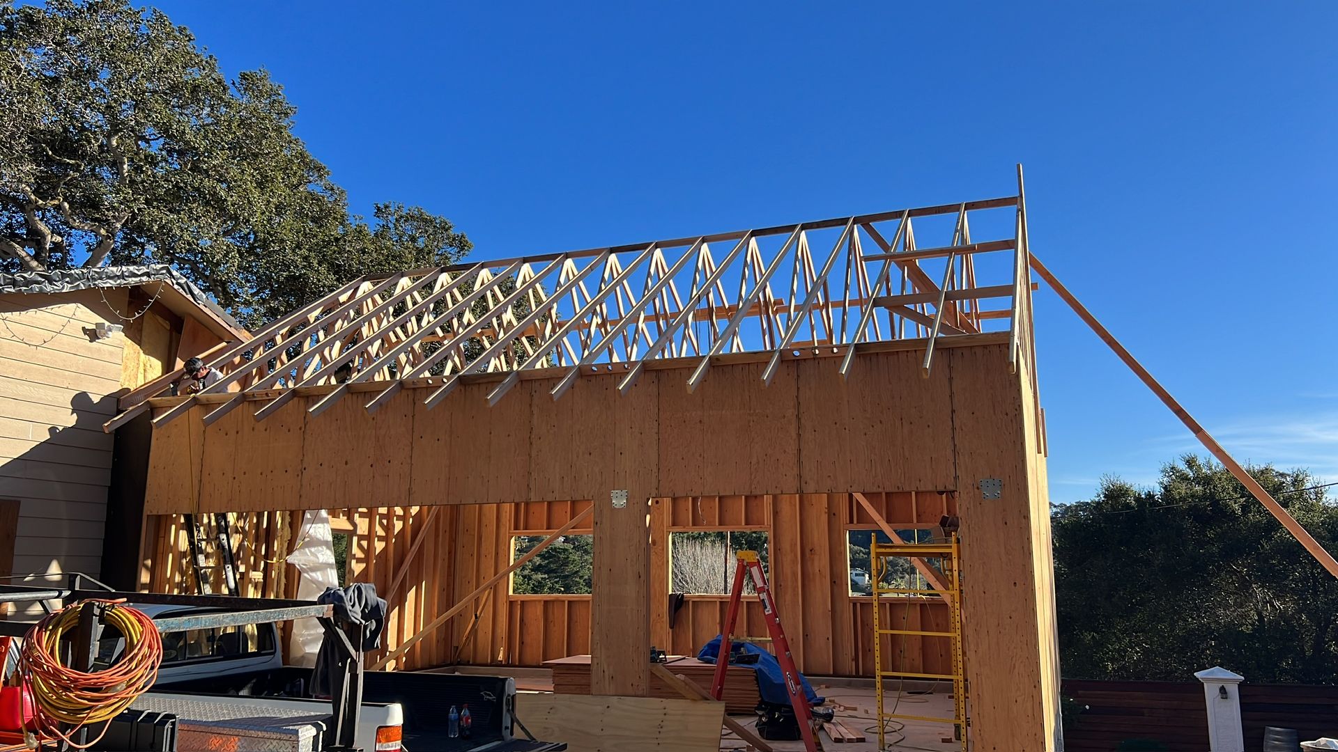Garage under construction; wooden frame, open roof, blue sky.