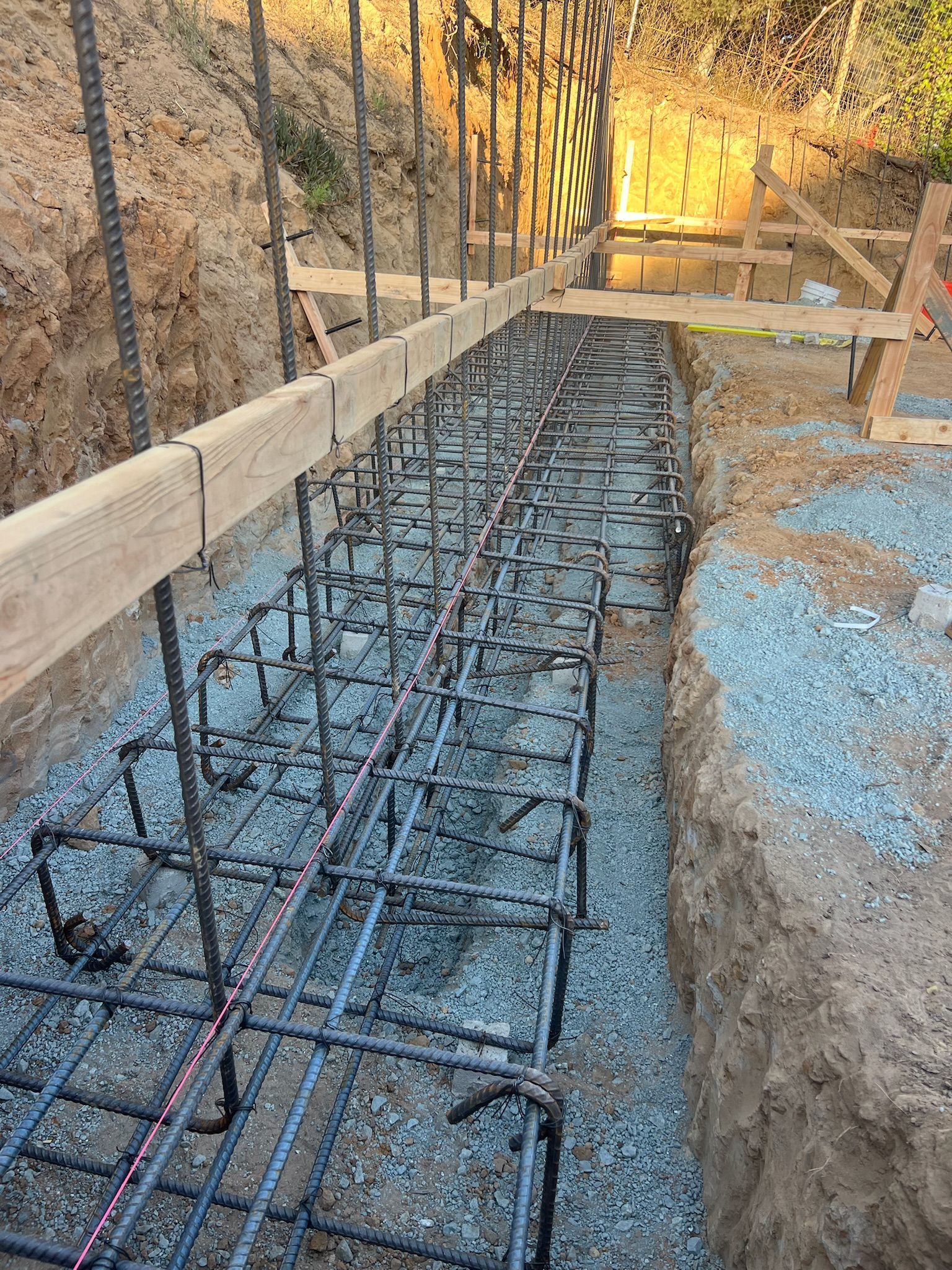 Foundation construction: rebar framework within a trench, ready for concrete pour.