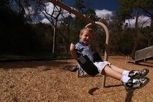 A young child on a swing at Cofrin Park.