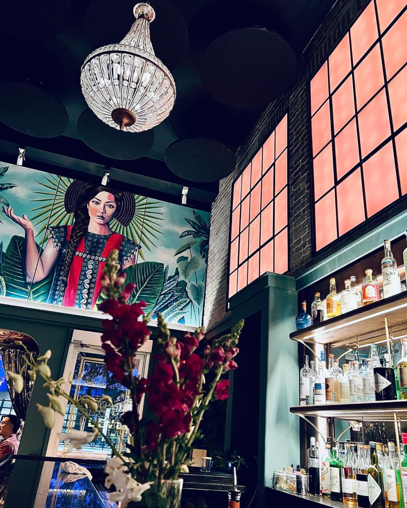 The chandelier, stained glass and painting of a women on the wall of Kin Bar.