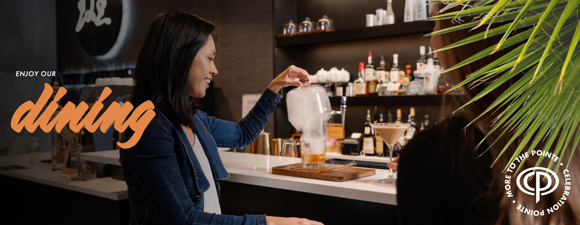 A woman opening a smoked cocktail in a restaurant in Celebration Pointe.