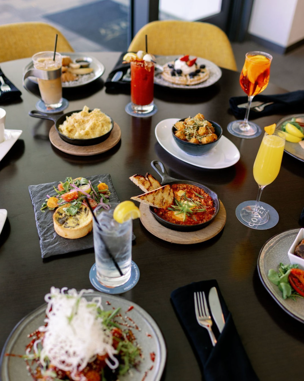 A large table full of brunch options, as well as mimosas and cocktails at Covey Kitchen.