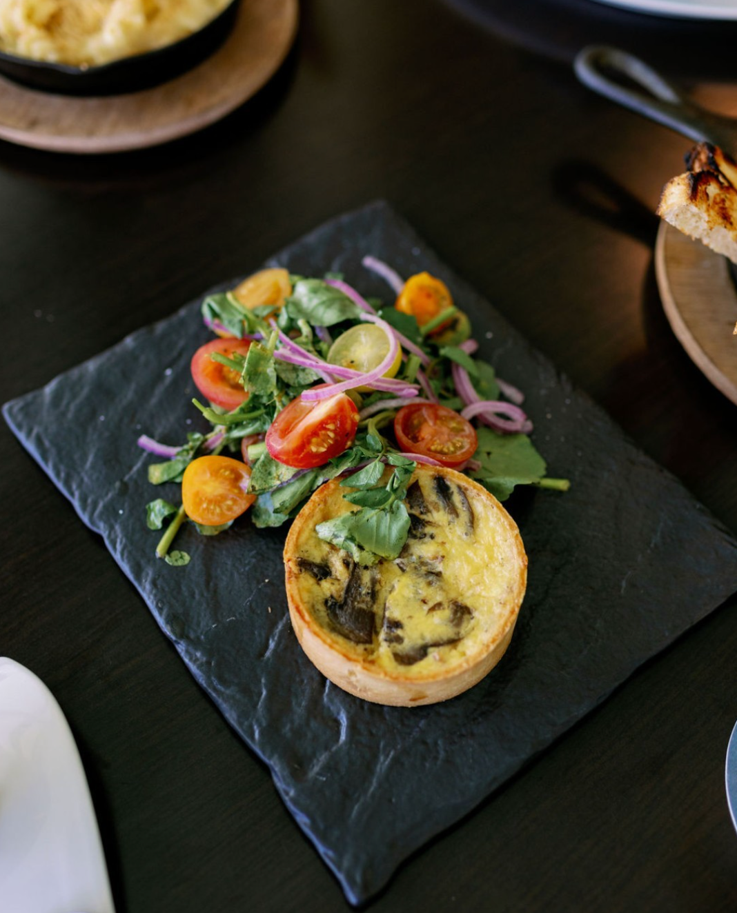 A plate with salad and tomatoes alongside an entree.