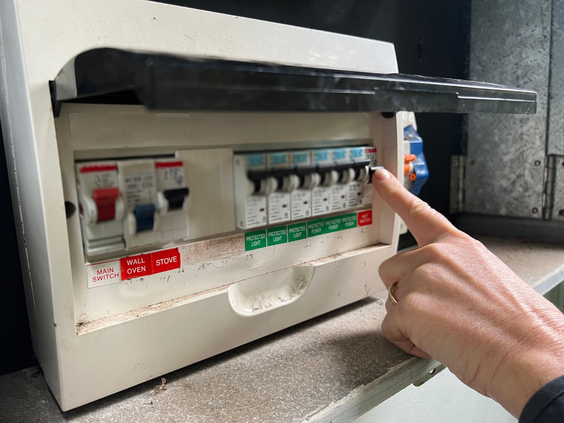 A person is pointing at an electrical box with their finger.
