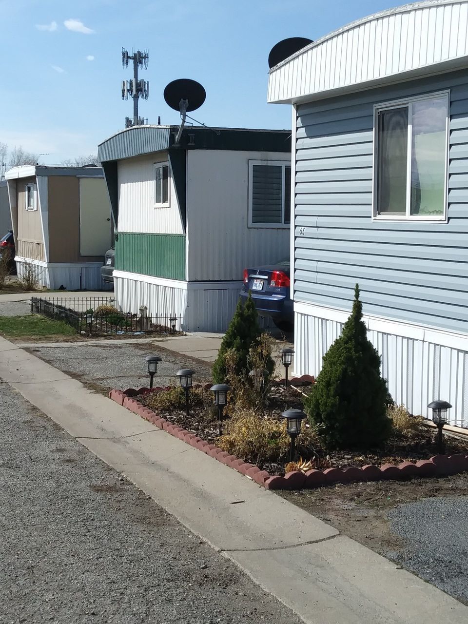 Front of a mobile home with trucks in the driveway at South Springville Mobile Home Park
