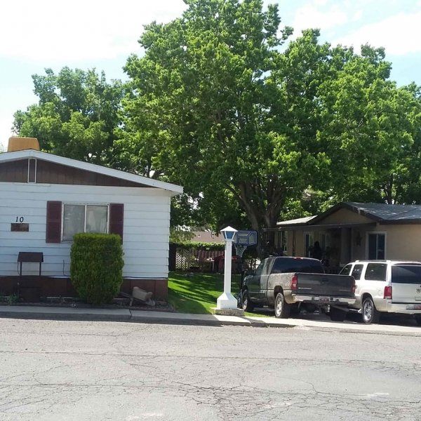Front of a mobile home with trucks in the driveway at South Springville Mobile Home Park