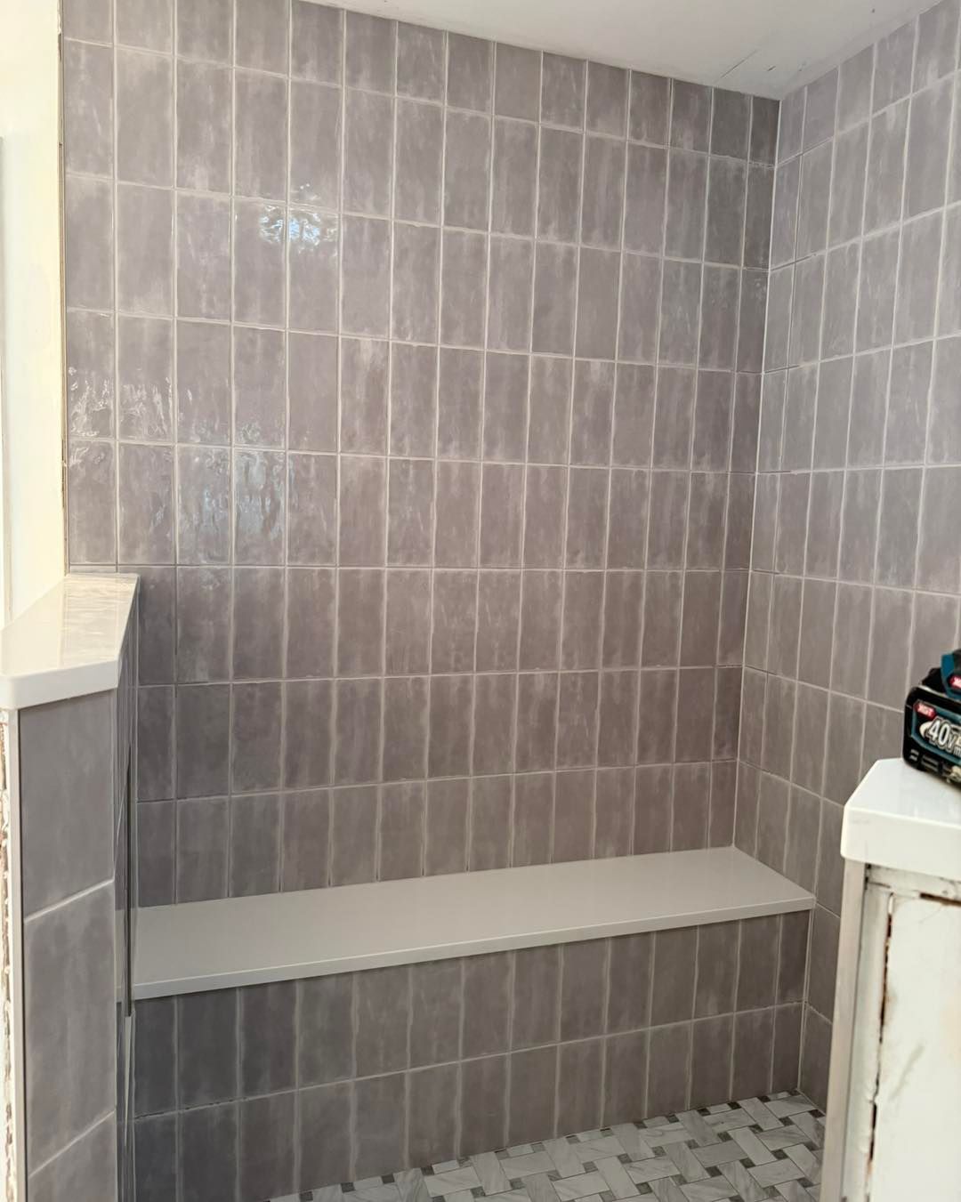 Gray tiled shower with a bench.