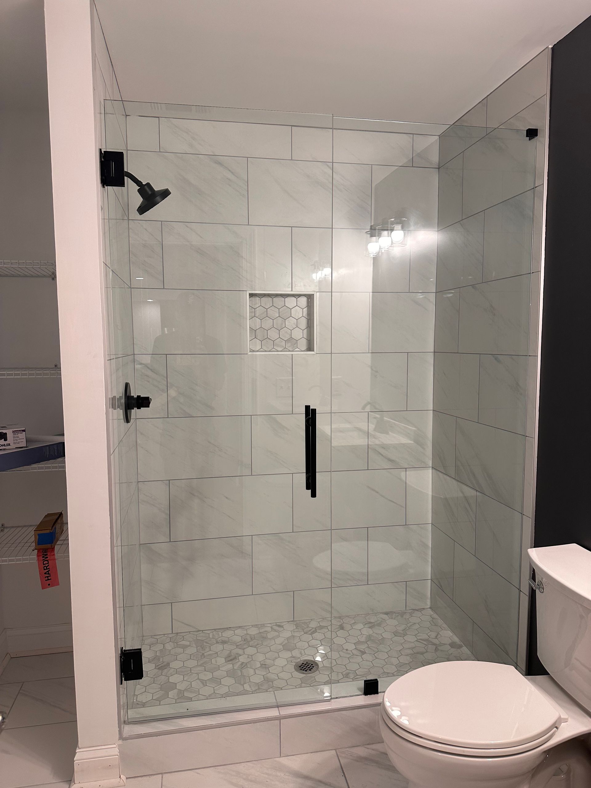 Bathroom with tub, tiled walls, small window, and glass shower surround.