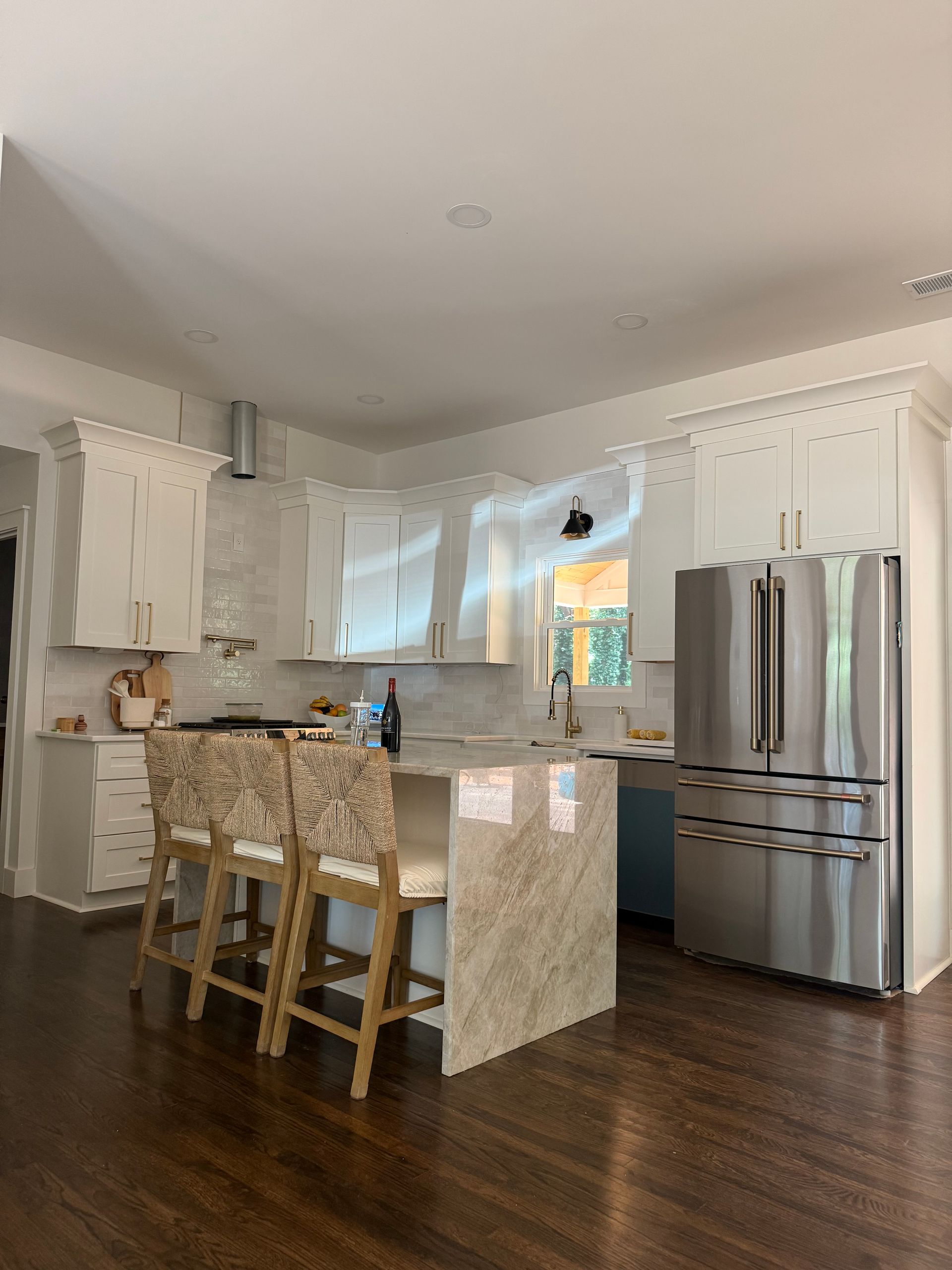 White kitchen with stainless steel appliances, hardwood floors, and a dining area.