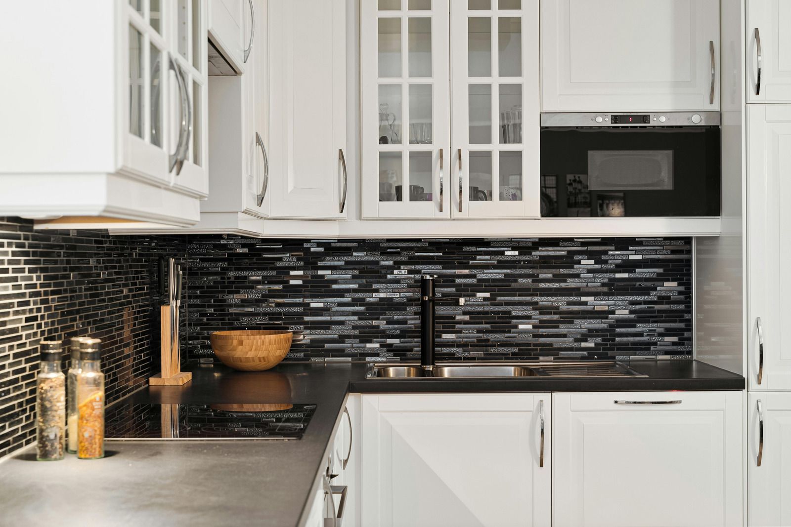 White kitchen with black tile backsplash and countertop.