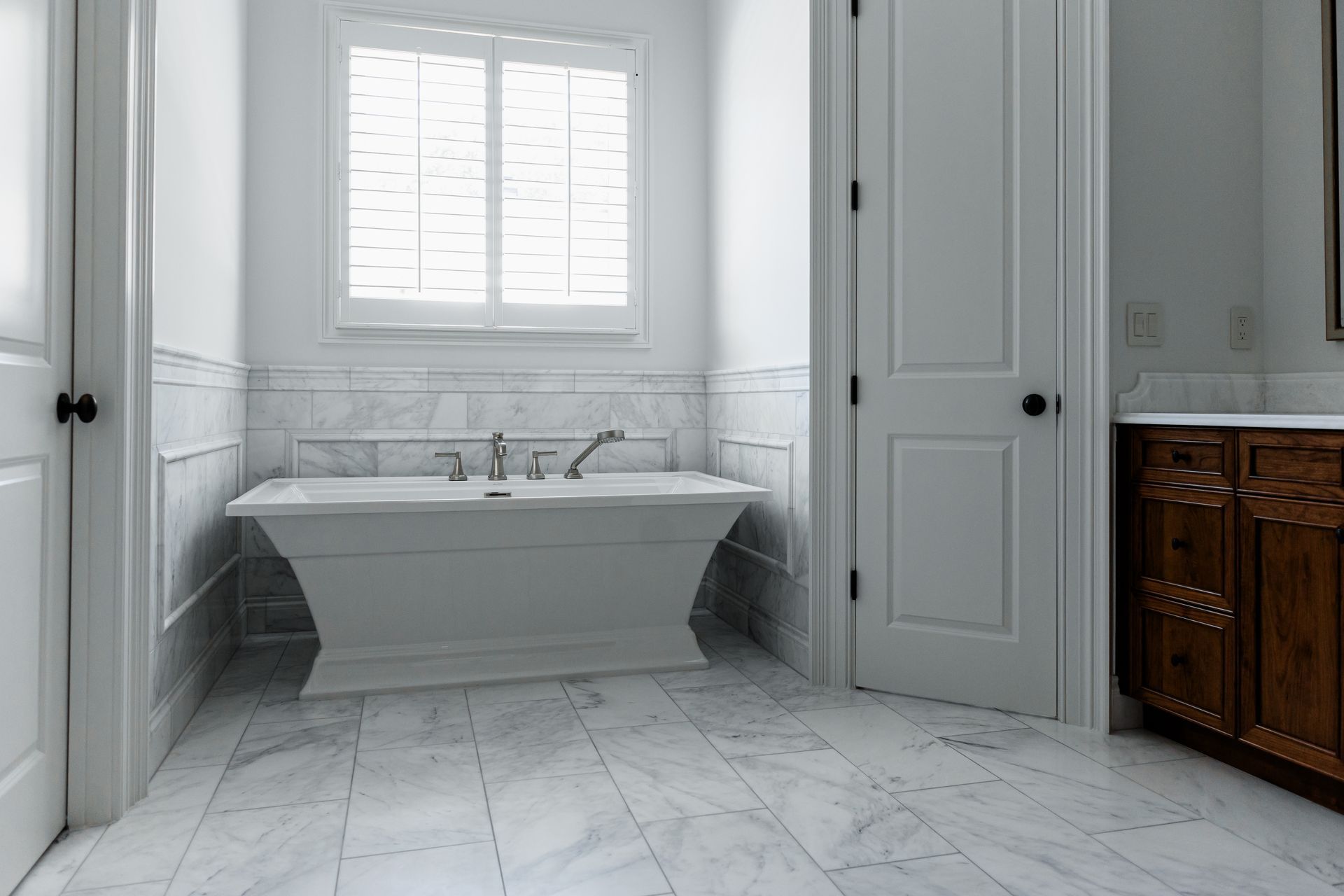 Modern bathroom with freestanding tub, glass shower, and stone walls.