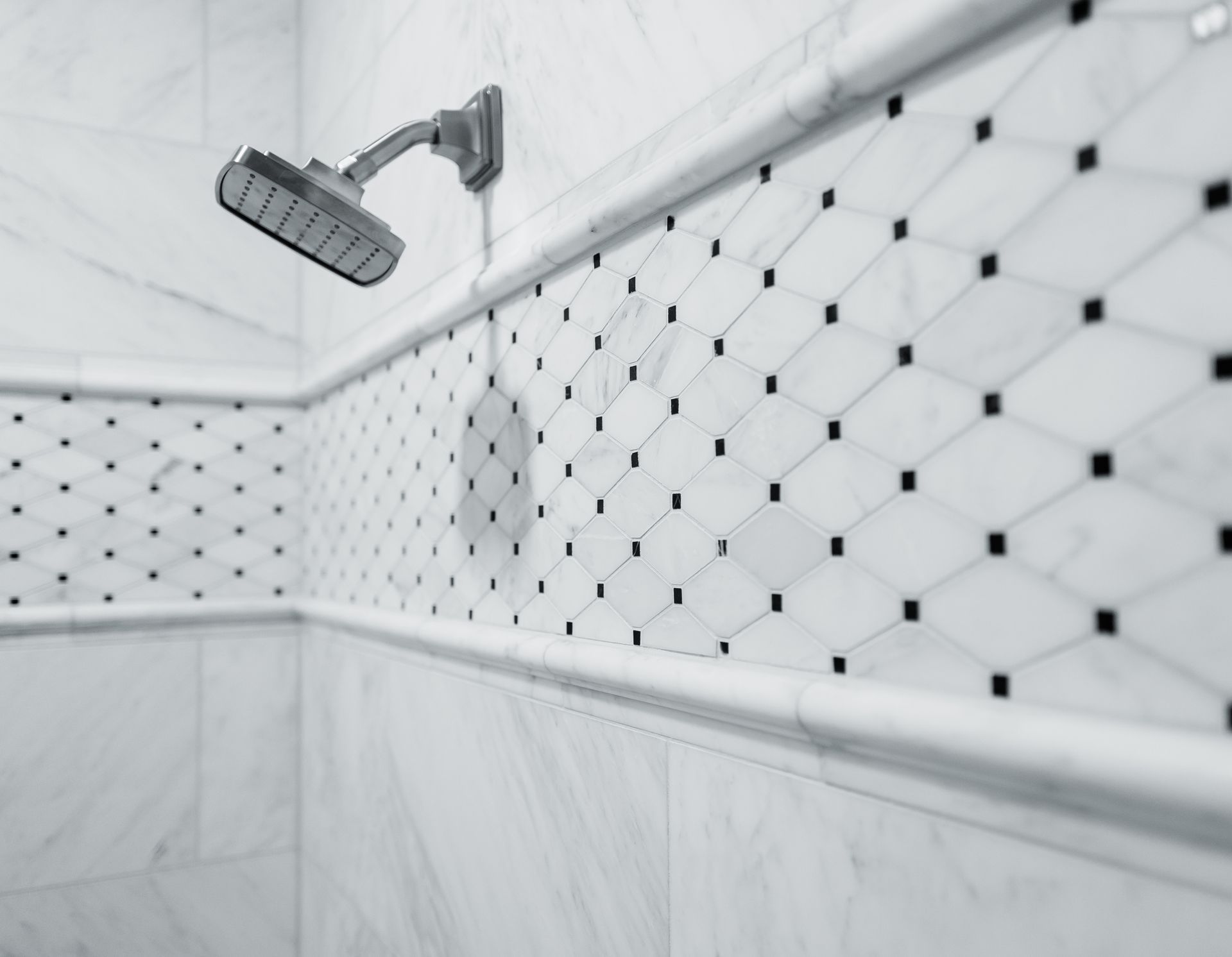 Bathroom with marble walls, black fixtures, and a skylight.