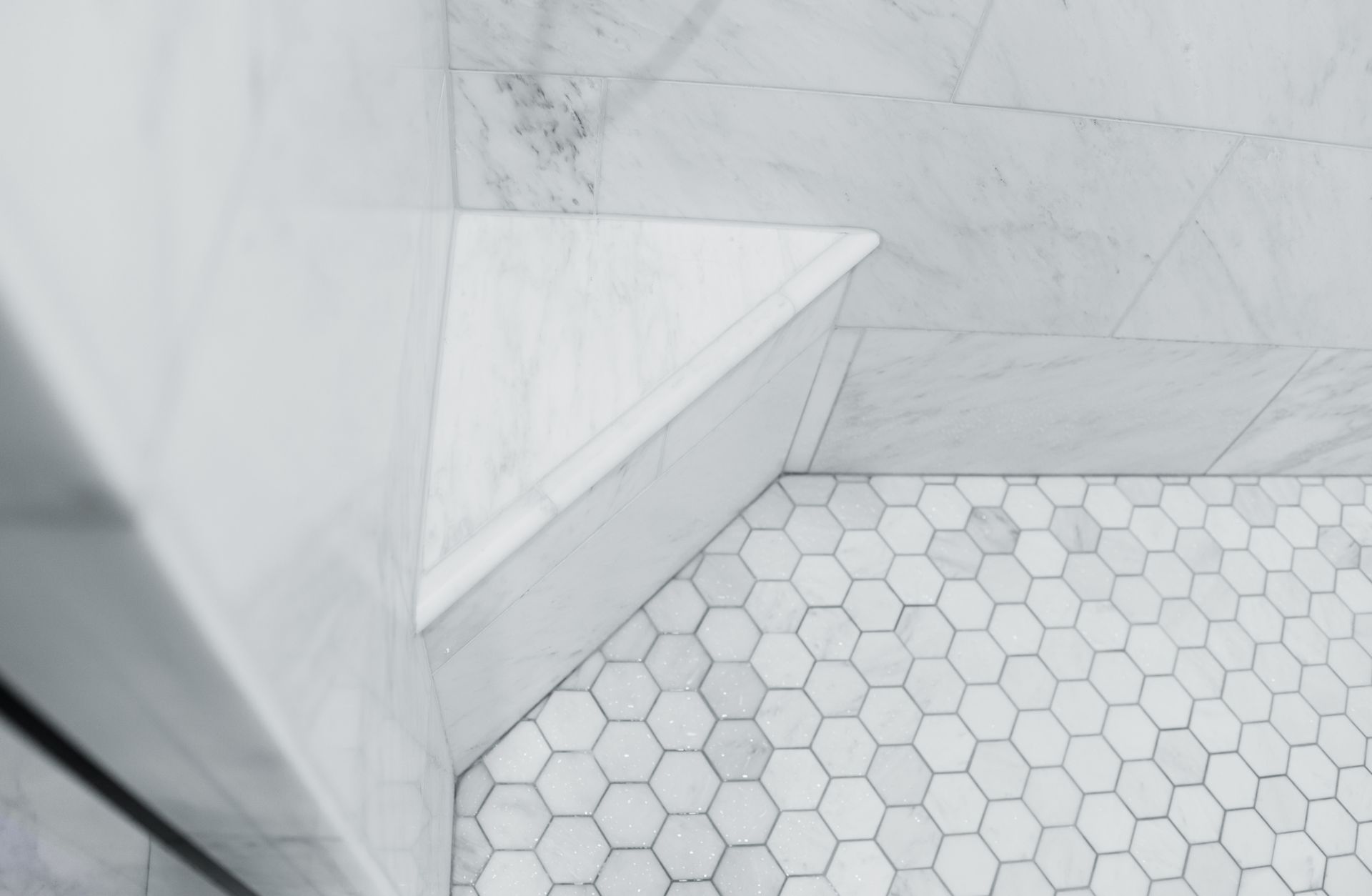 Spacious, light-filled bathroom with marble walls and floors. A large tub and large windows.