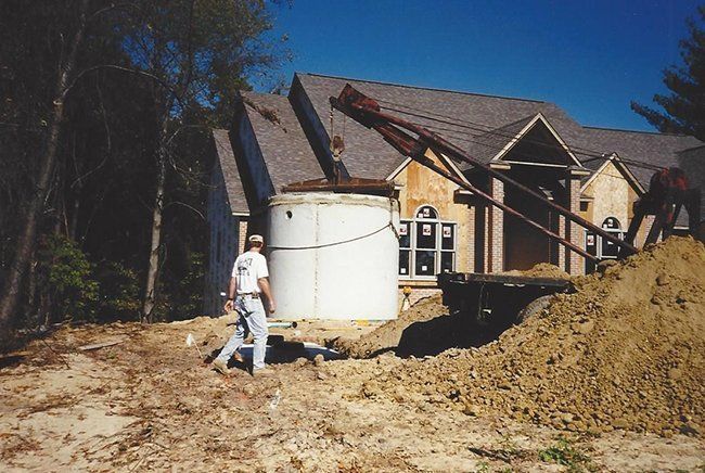 Man Assisting Septic Tank Lowered Into Ground — Plymouth, IN — Creed Septic System Specialist