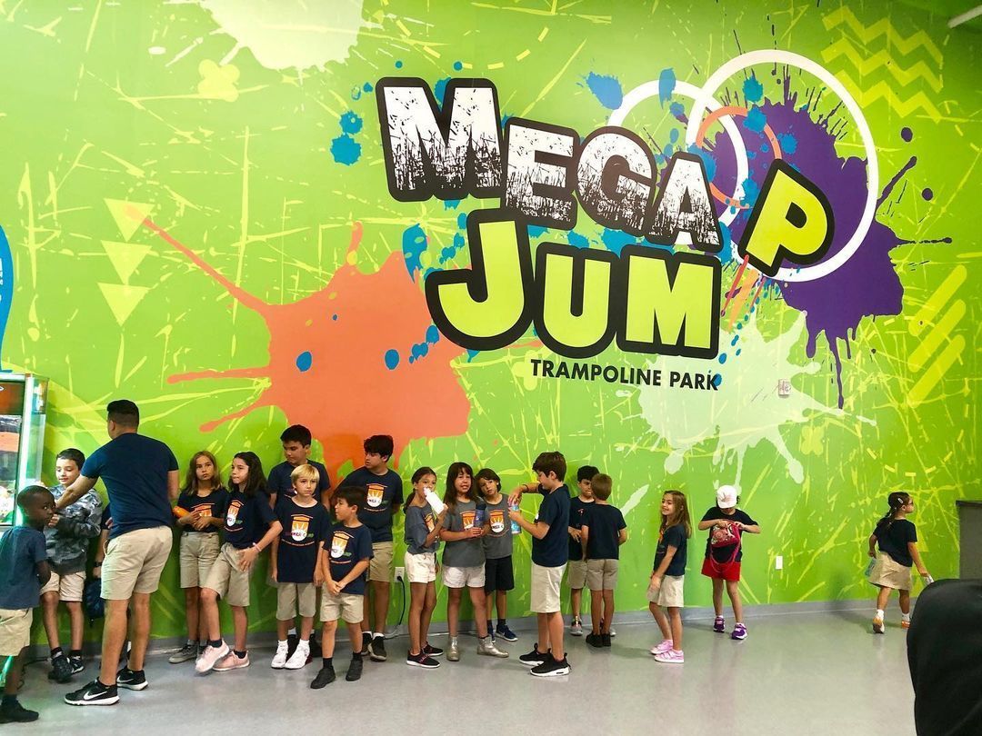 Group of children at Mega Jump Trampoline Park, in front of a lime green wall with the logo